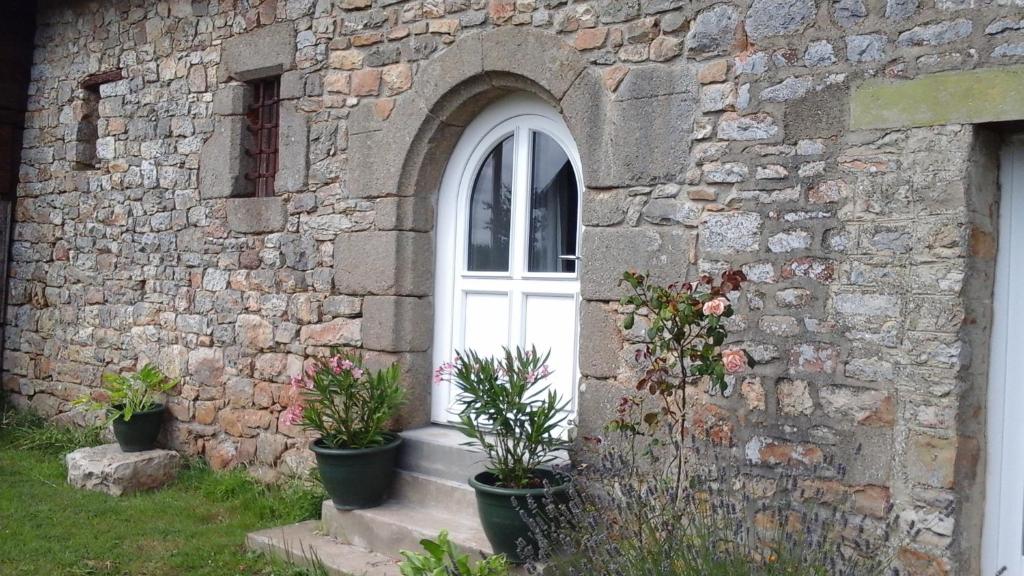 un edificio de piedra con ventana y macetas en Chambre d'hôtes La Ruzardière, en Combourtillé