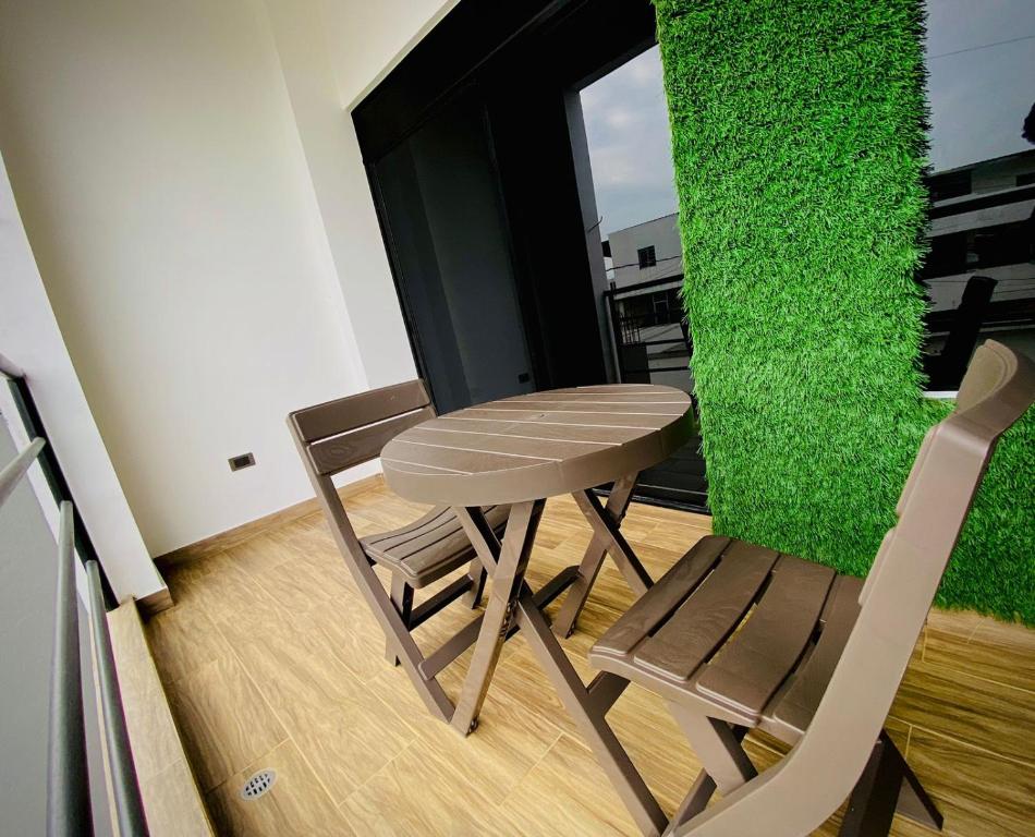 a table and chair in a room with a green wall at Departamento 2 Habitaciones con Balcón a 10min Consulado Americano in Guayaquil