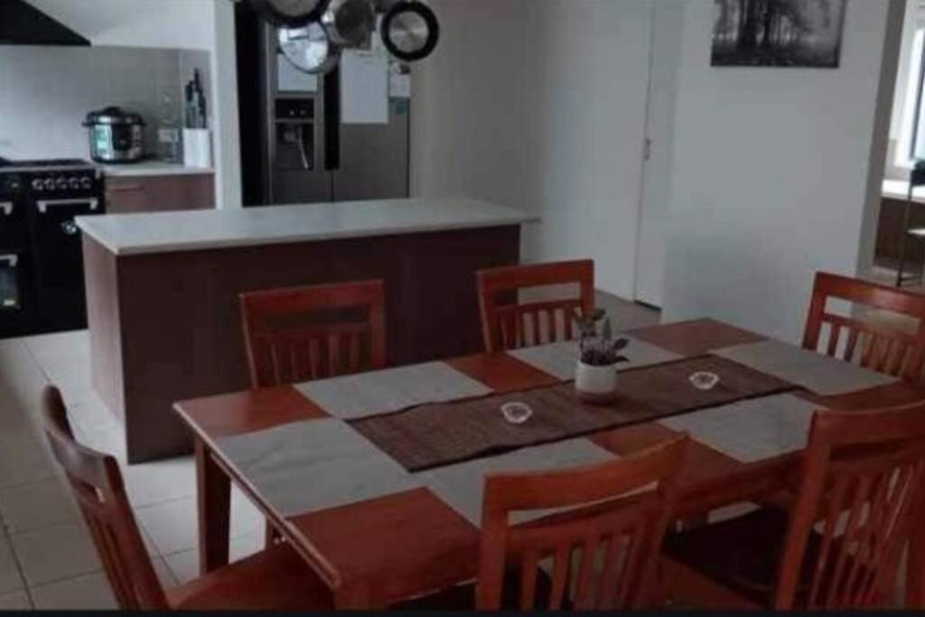a table and chairs in a kitchen with a table and a counter at Family home close to Melb Airport, free FAST WIFI! in Craigieburn