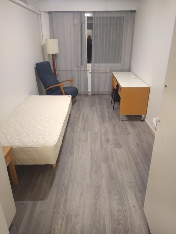 Una pequeña habitación con una cama y un escritorio. en Hostelli tornihovi, en Kouvola
