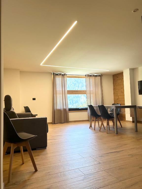 a living room with chairs and a table and a window at Baita del Sole in Vermiglio