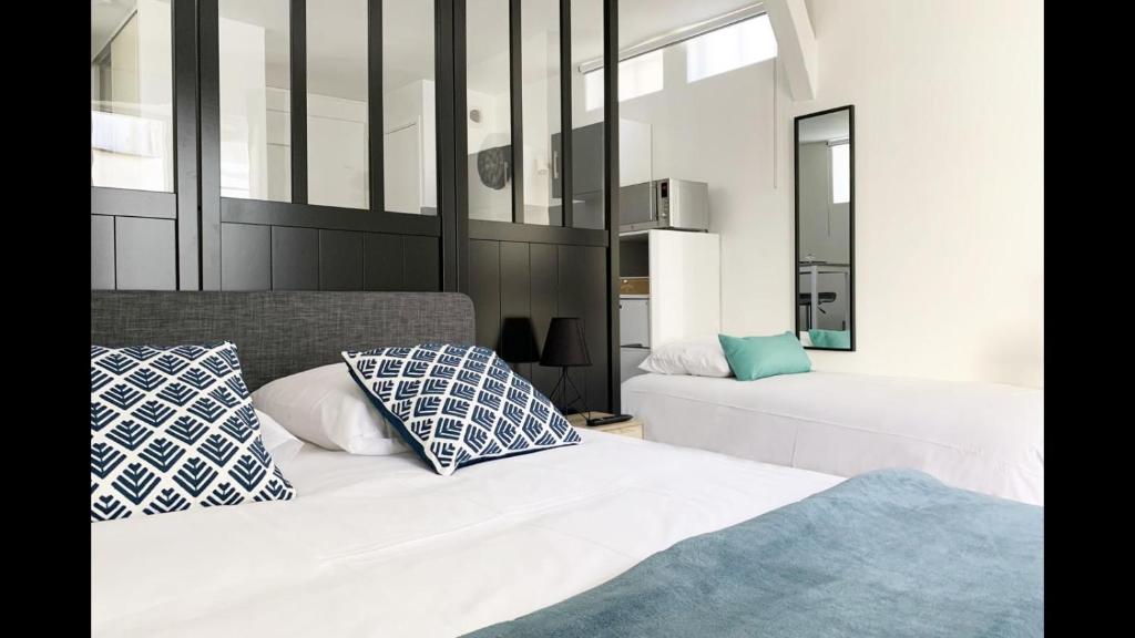 - une chambre avec 2 lits dotés d'oreillers bleus et blancs dans l'établissement La Petite Cour, à Chartres