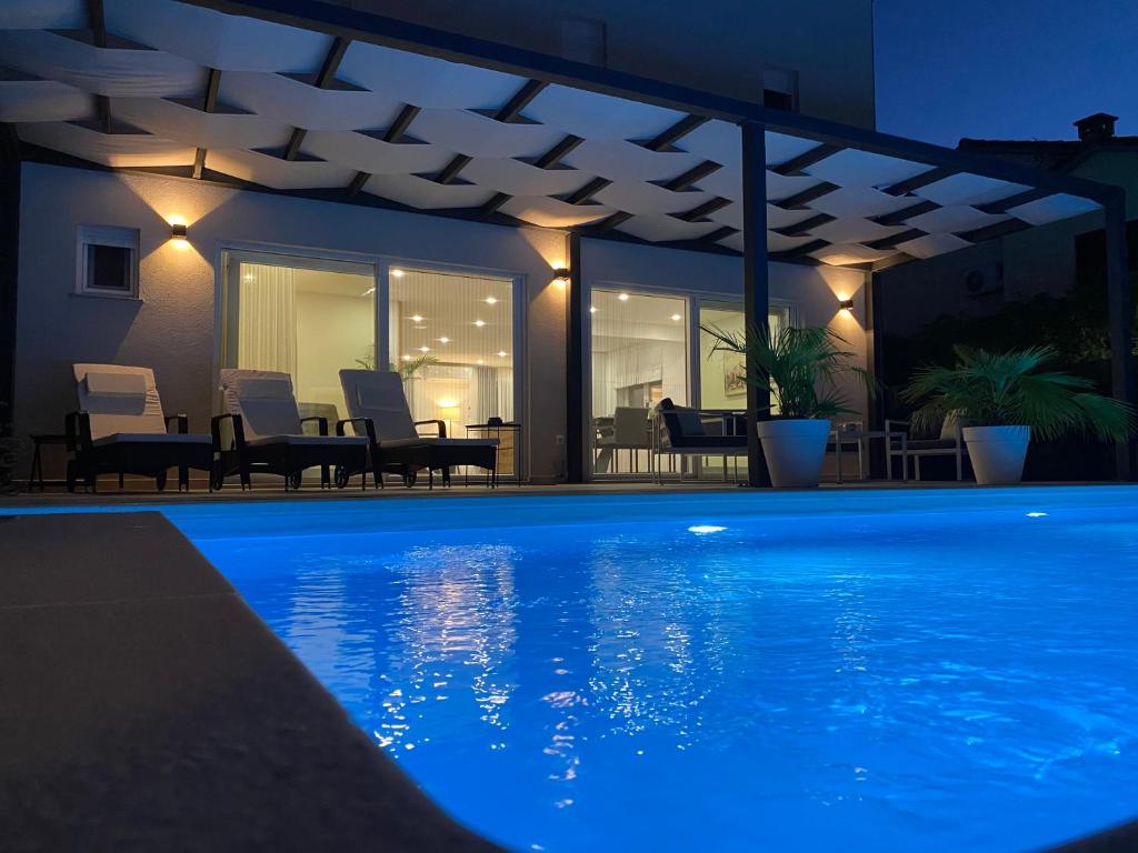 una casa con piscina por la noche en Villa Adria, en Privlaka