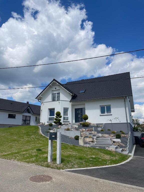 une maison blanche avec un panneau devant dans l'établissement Chez manu, à Voellerdingen