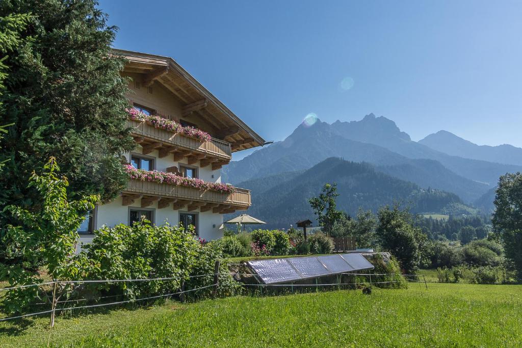a building with a solar panel in a field with mountains at Faustlinghof in Saalfelden am Steinernen Meer