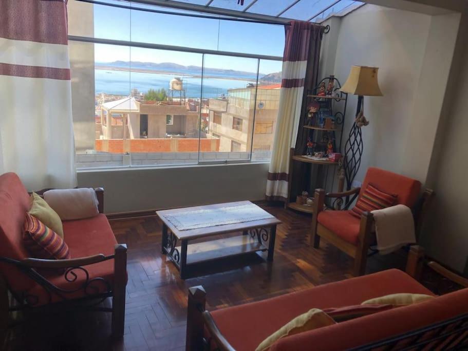a living room with a couch and a table and a large window at Apart House Happy CATA 001 in Puno