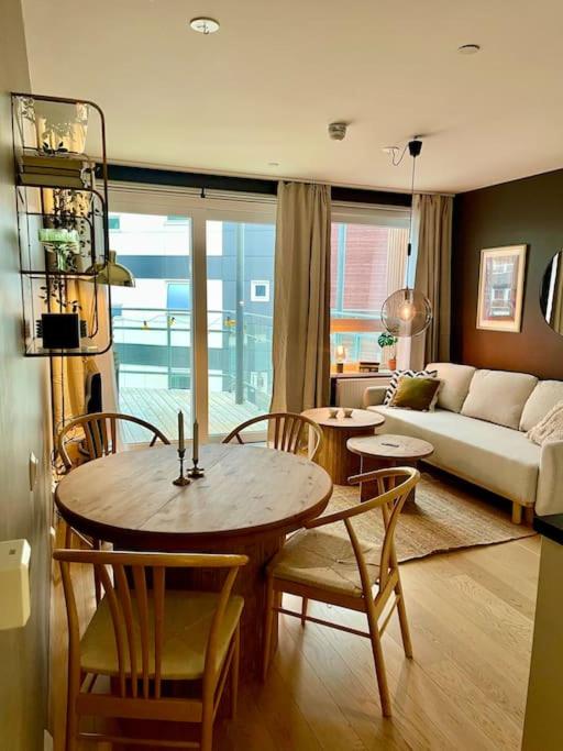 un salon avec une table, des chaises et un canapé dans l'établissement Nordisk moderne leilighet med parkering, à Tomasjorda