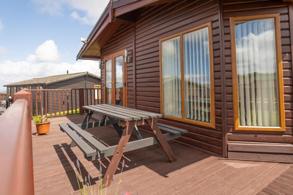 a wooden cabin with a picnic table and a bench on a deck at 5 Ocean View in Woolacombe