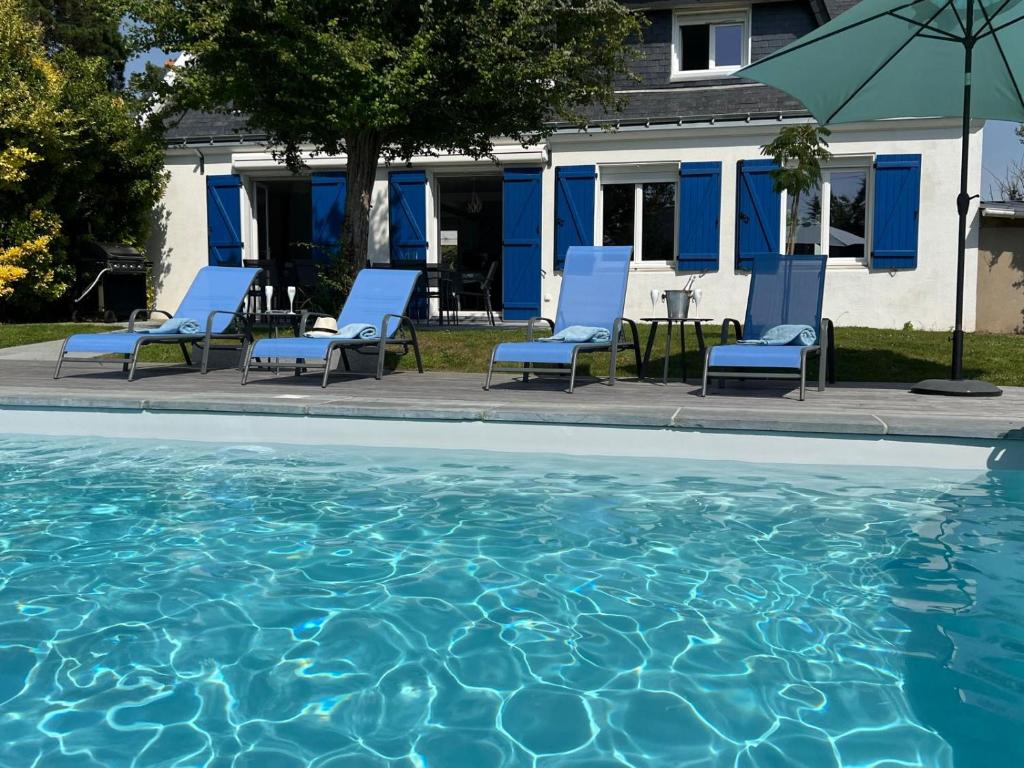 - une piscine avec des chaises, une table et un parasol dans l'établissement Belle Villa, piscine chauffée et proche plages, à Erdeven