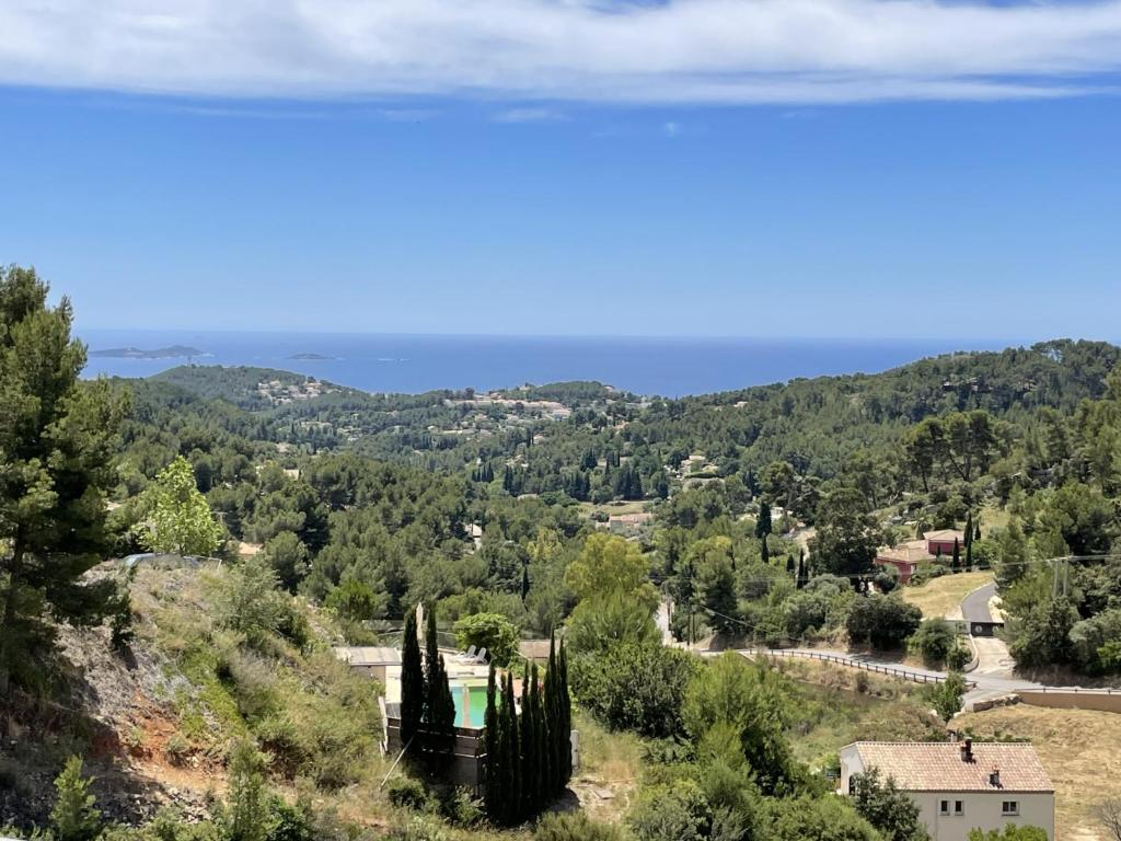 Elle offre une vue sur une vallée avec des arbres et l'océan. dans l'établissement Haut de villa, vue mer panoramique, à La Cadière-dʼAzur