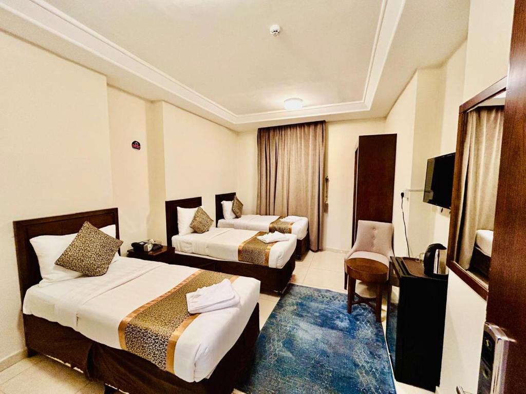 a hotel room with two beds and a television at Knooz Aldiafah in Makkah