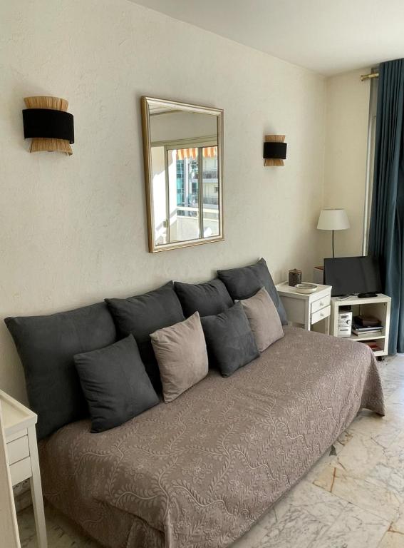 - un grand canapé gris dans le salon avec un miroir dans l'établissement studio standing cannes croisette, à Cannes