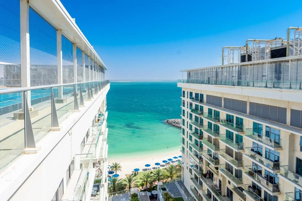 uitzicht op het strand vanaf het balkon van een gebouw bij Oceanfront Coastal Apartment in Ras al Khaimah