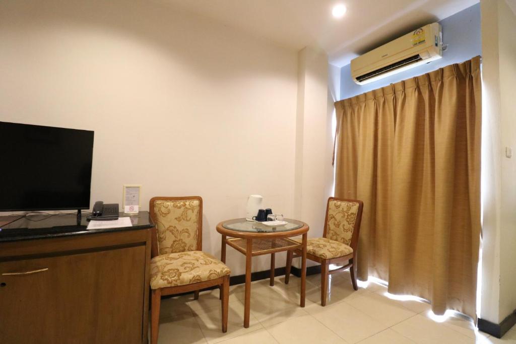 A sitting and entertainment corner with two upholstered chairs, a small table and a wall-mounted TV.