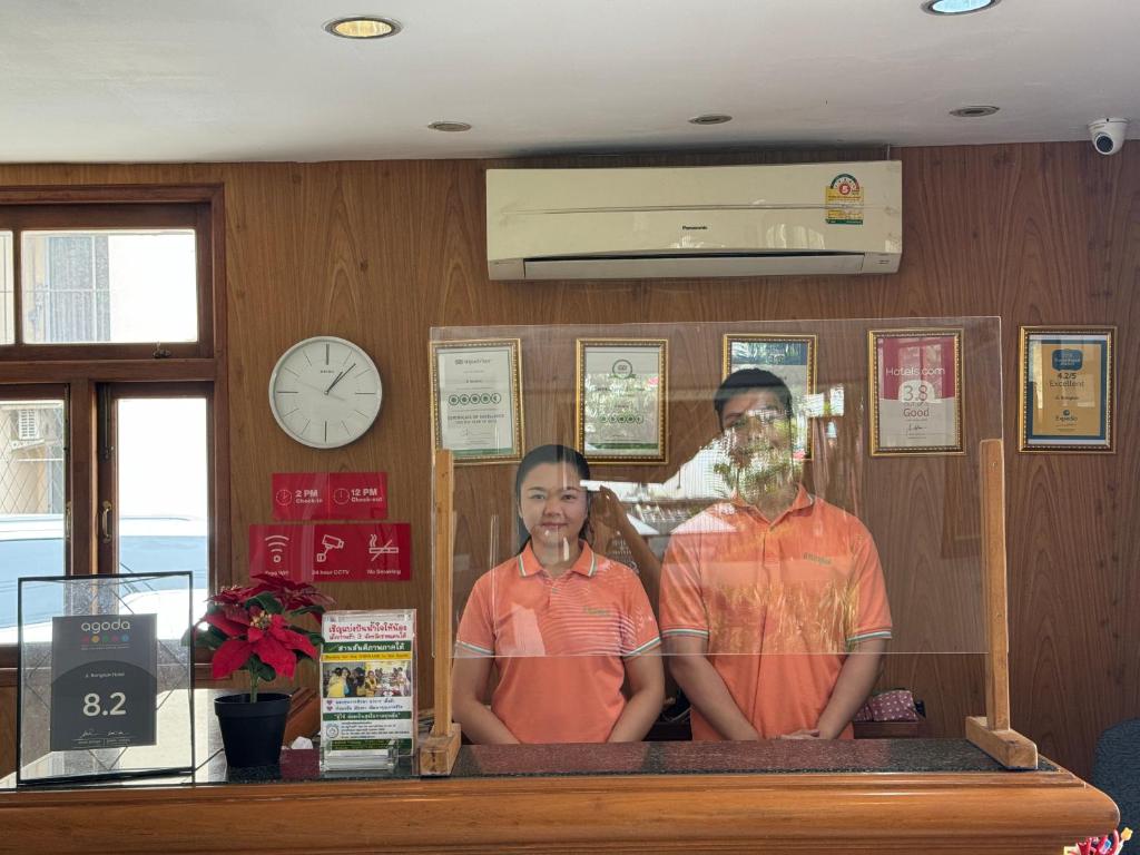 Reception staff stand behind a glass-screened wooden front desk.