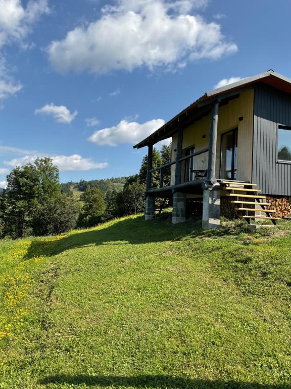 a building on a hill with a grass field at Котедж На Лузі in Verkhne-Studënyy