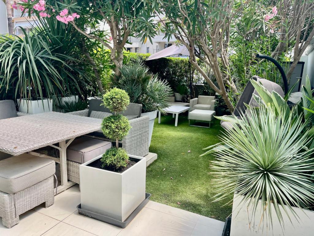 un patio avec une table, des chaises et des plantes dans l'établissement Jardin sur la Pointe Croisette Luxe en Bord de Mer, à Cannes