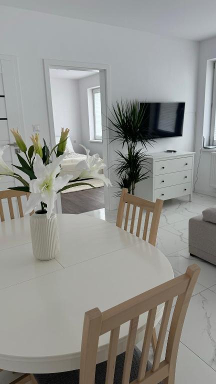 a white table with a vase of flowers in a living room at Apartament Grójec in Grójec