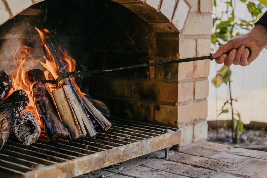 a man is cooking food on a grill at Cow Bell Cottage in Trentham