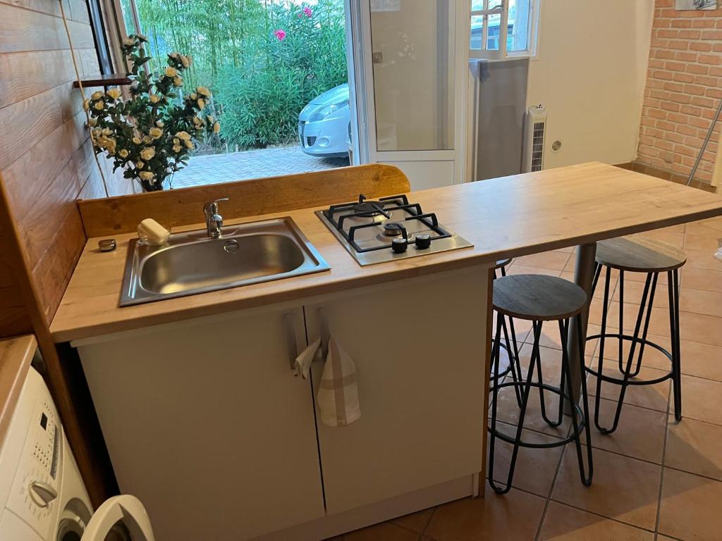 une cuisine avec un évier et un comptoir avec des tabourets dans l'établissement 2 pieces hortensias, à Mandelieu-la-Napoule
