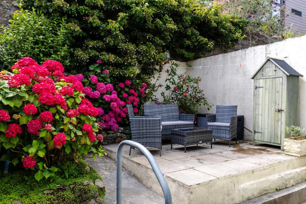 a group of chairs and flowers next to a fence at Beach Haven, Steps to Sand, Trails & Shops, Highly Rated 2-Bedroom House Minutes from Mumbles Beach with a Patio in Oystermouth