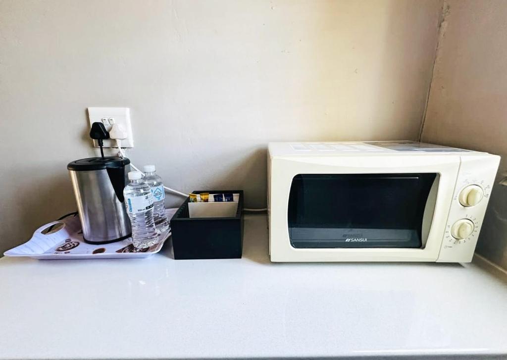 a microwave sitting on a counter next to a coffee maker at Siyaya Sbosh BnB in Reitz