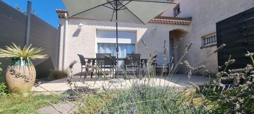 un patio avec une table, des chaises et un parasol dans l'établissement Nid douillet au pied du Vercors, à Eymeux