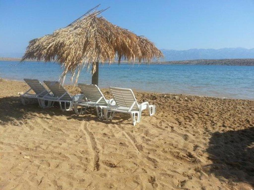 two lounge chairs and a straw umbrella on a beach at Apartment Nin 531 in Nin
