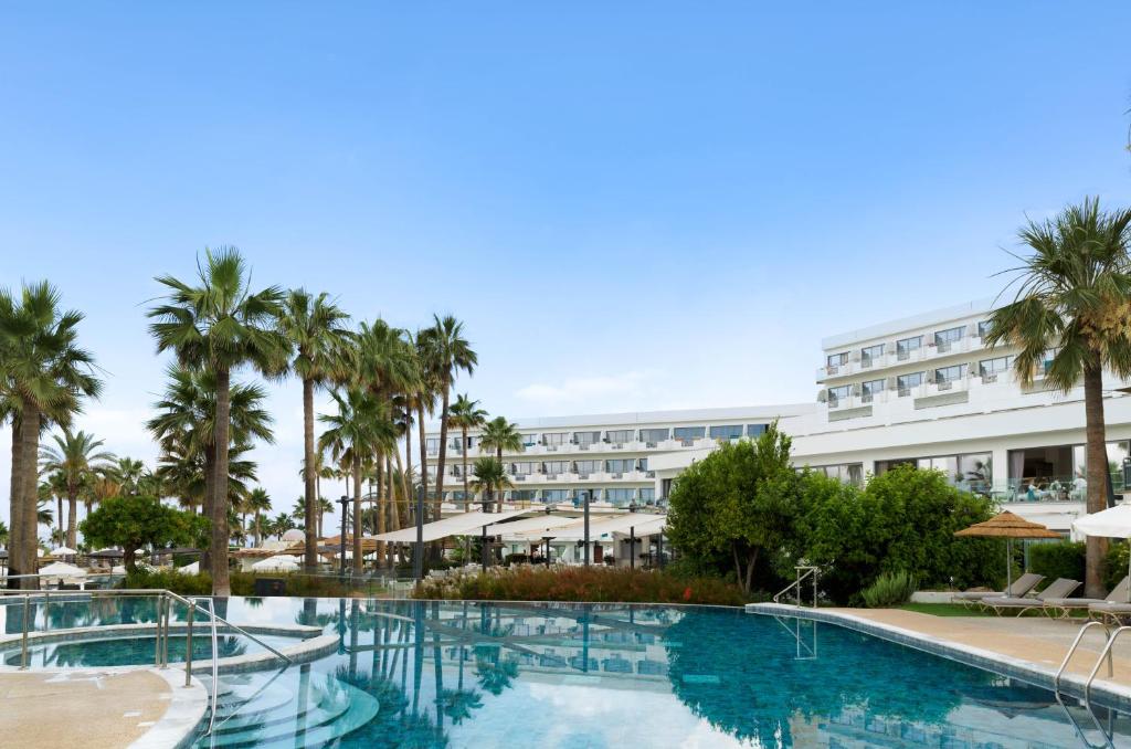 a resort with a swimming pool and palm trees at St George Beach Hotel & Spa Resort in Paphos