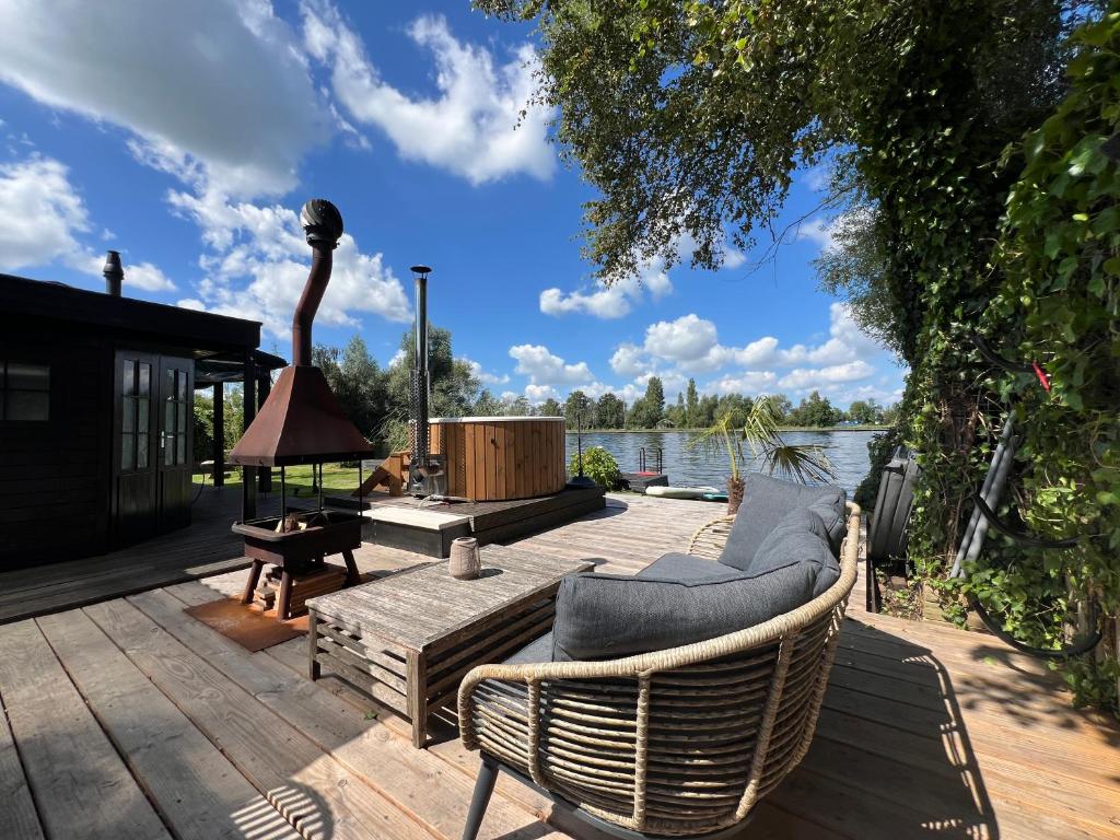 a deck with chairs and a table and a grill at New- The Cabana- With Sauna and Hot Tub, on a lake near Amsterdam in Vinkeveen