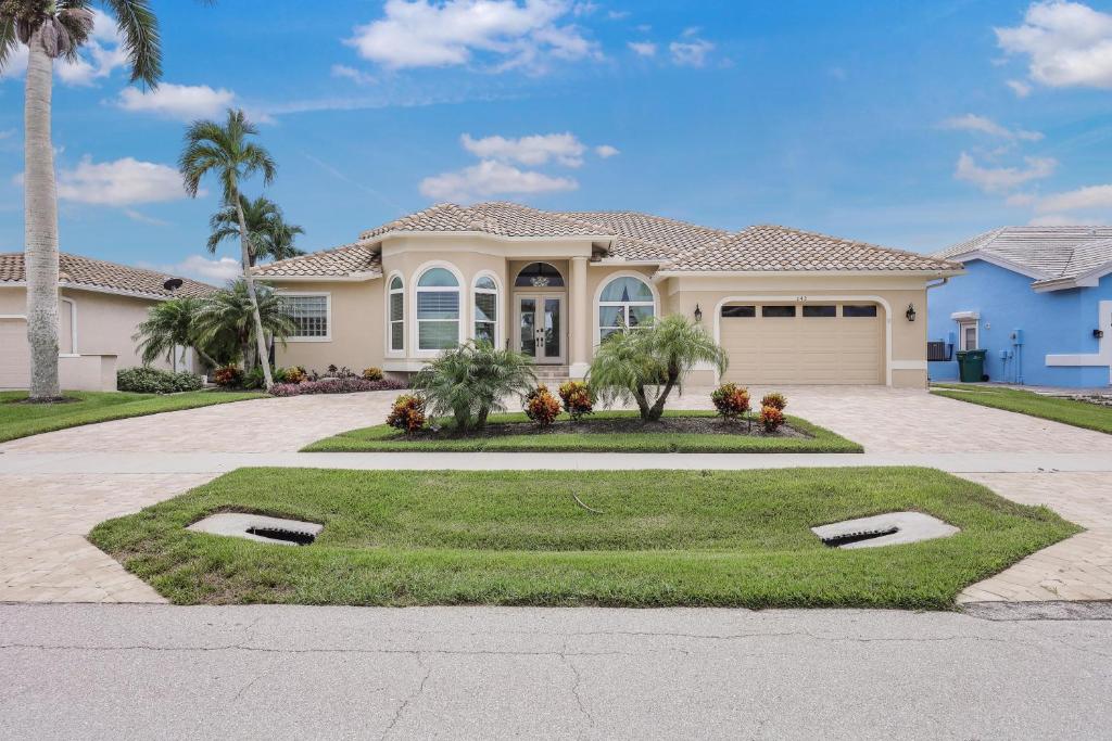 a large house with palm trees in the driveway at Alluring waterfront home with W exposure, pool/dock in Marco Island