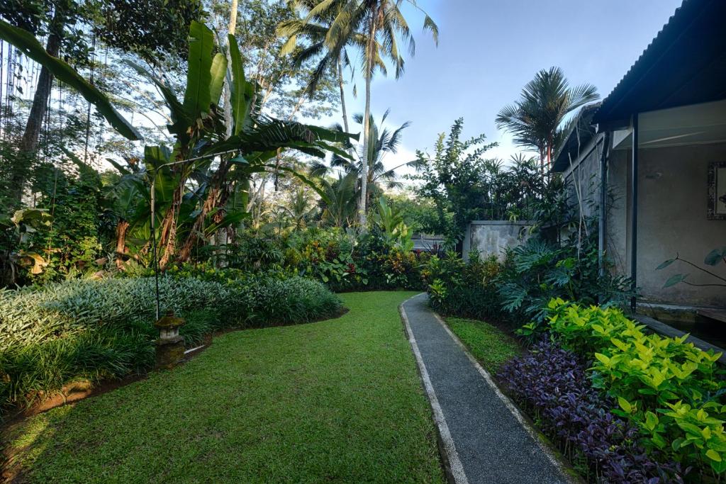 un jardín con una pasarela junto a una casa en Kaja Villa, en Ubud
