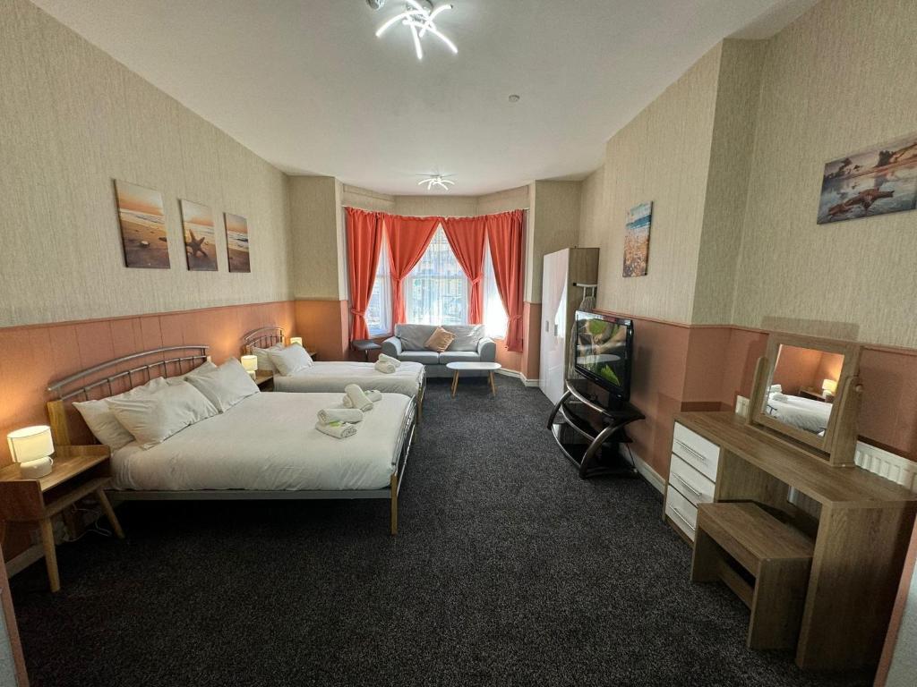 a bedroom with a bed and a tv and a couch at The Paradise Guest House in Great Yarmouth