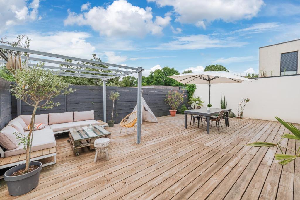 une terrasse avec un canapé, une table et un parasol dans l'établissement Le clos des Aviateurs - Belle maison à Strasbourg, à Strasbourg