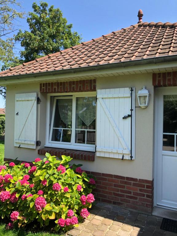 une maison avec des portes blanches et des fleurs roses dans l'établissement Chambre d'Hotes Les Hortensias, à Rang-du-Fliers