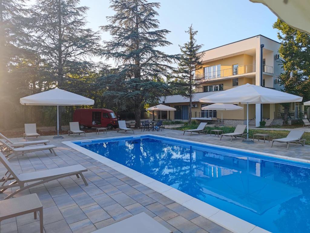 a pool at a hotel with chairs and umbrellas at Villa Ella in Ljubuški