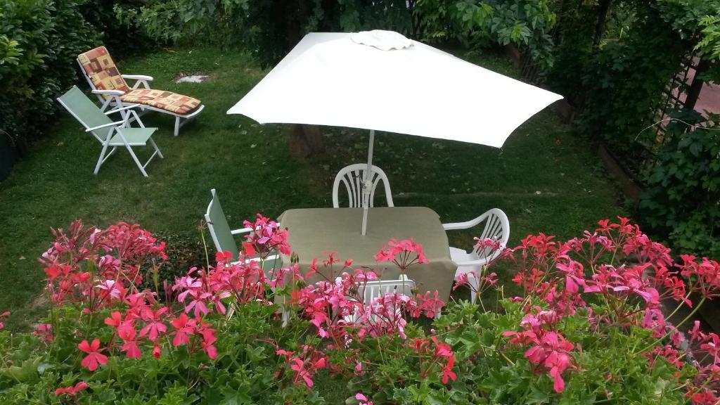 une table et des chaises avec un parasol et des fleurs dans l'établissement Aux chants des oiseaux, à Heudreville-sur-Eure