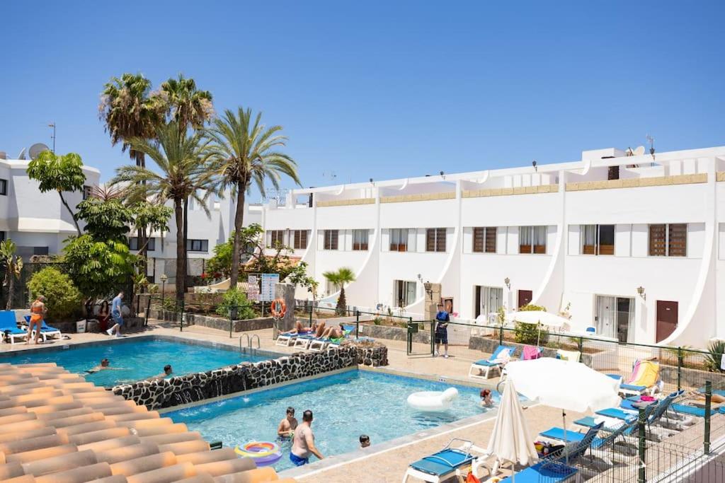 a swimming pool in front of a large white building at Dialez Holidays - Rebecca in Playa de las Americas
