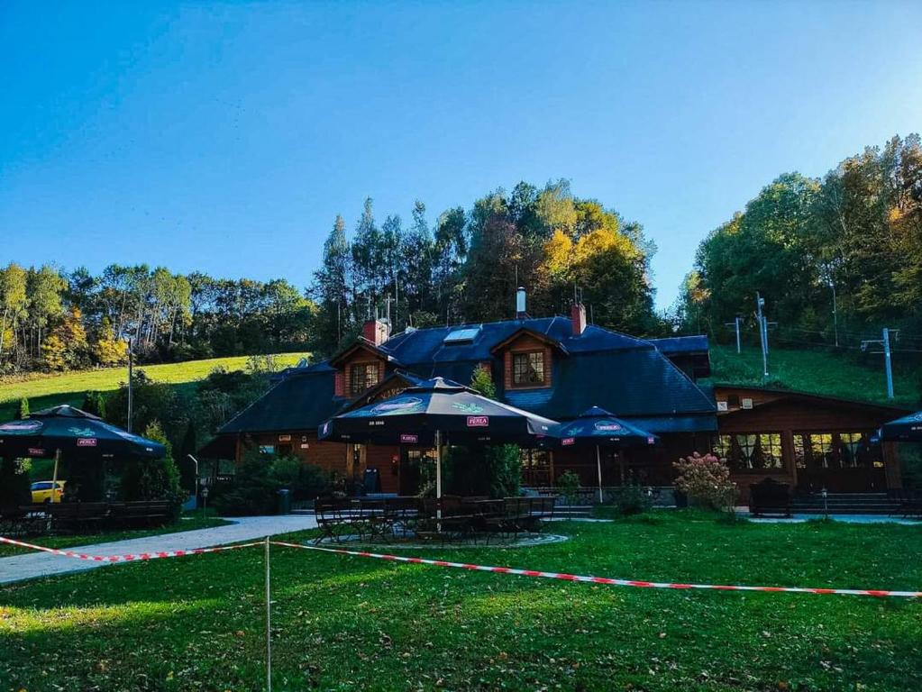 a house with blue umbrellas in the grass at Karczma Parchatka in Kazimierz Dolny