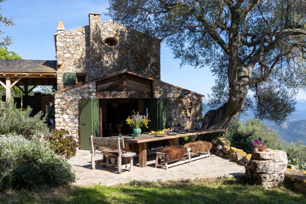 una casa in pietra con un tavolo da picnic e un albero di Magnifique Bergerie AMORE vue panoramique mer et montagne a Cargèse