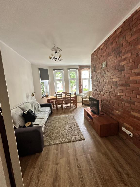 a living room with a couch and a brick wall at Mazurski klimat in Ełk
