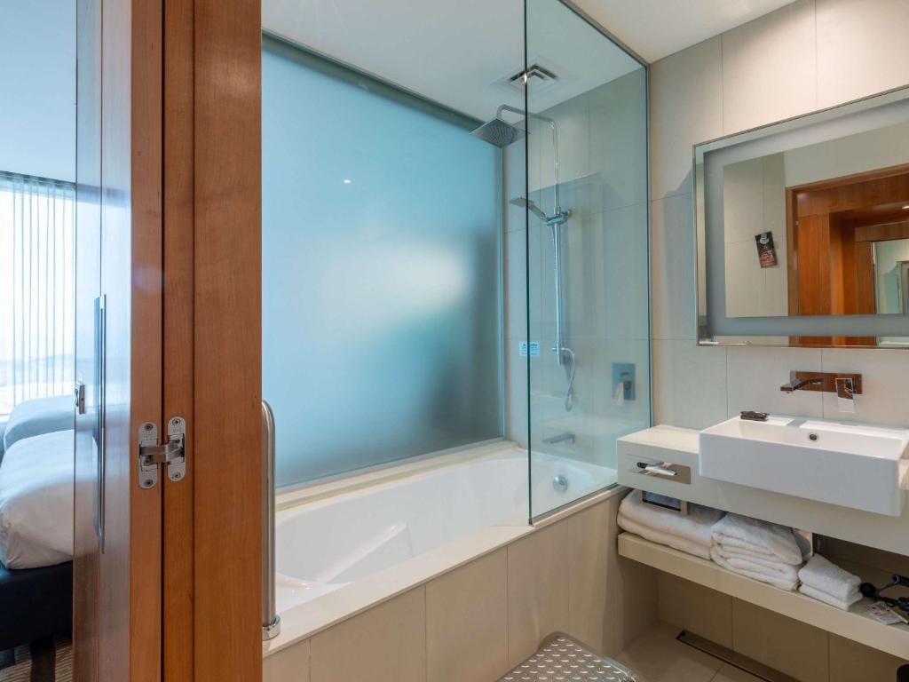 a bathroom with a tub and a sink and a shower at Novotel Auckland Airport in Auckland