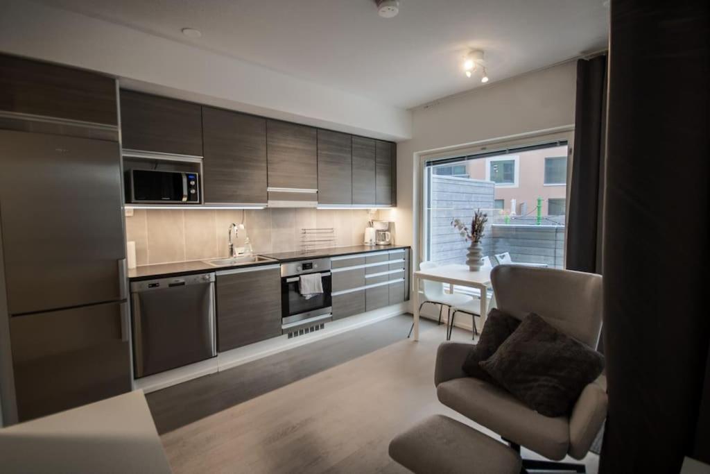 a kitchen with brown cabinets and a chair and a table at Brand new studio apartment near the harbour in Turku