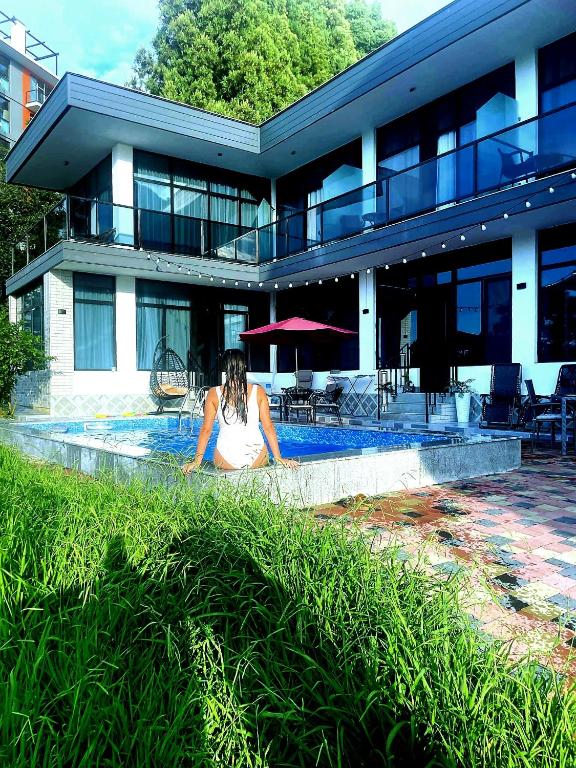 a woman sitting by a swimming pool in front of a building at sea side in Makhinjauri