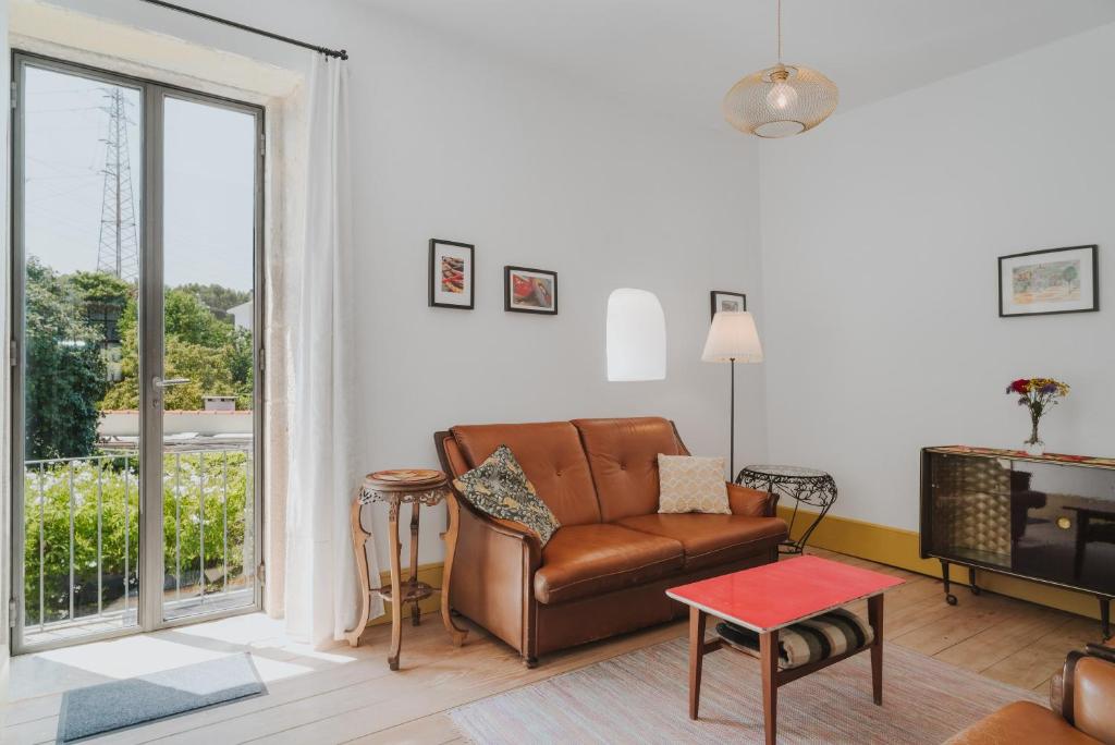a living room with a leather couch and a table at Casa do Mestrinho 2 in Avintes