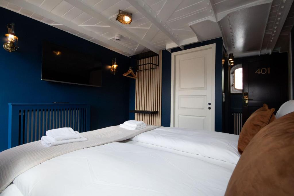 two beds in a blue room with two towels on top at Mälardrottningen Yacht Hotel in Stockholm