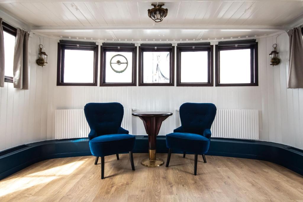 two chairs and a table in a room with windows at Mälardrottningen Yacht Hotel in Stockholm