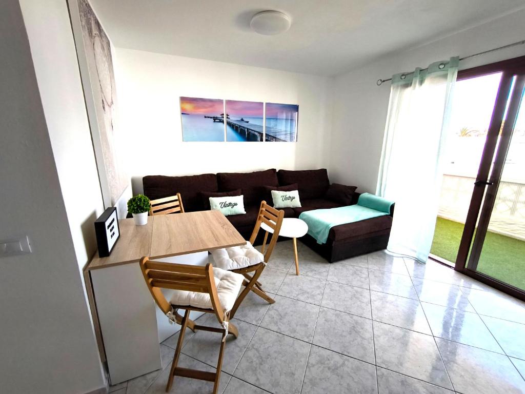 een woonkamer met een bank, een tafel en stoelen bij Apartamento OCEAN PEARL in Corralejo