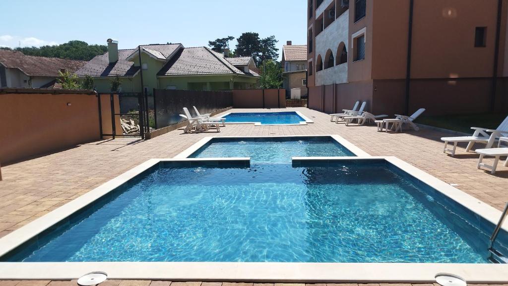 een zwembad met stoelen en een gebouw bij Apartman NEMANJA in Vrnjačka Banja
