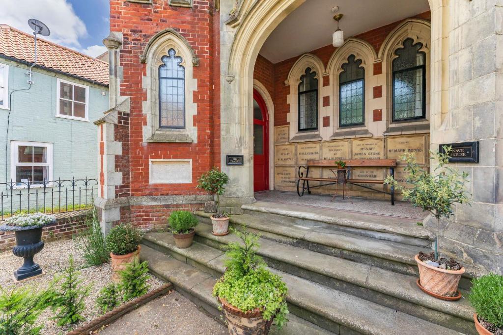 a building with a red door and a table in front at The Tracery - Norfolk Cottage Agency in Fakenham